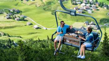 Due persone sulla seggiovia di piacere di Sareis con vista sulla valle verde sullo sfondo