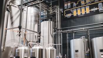 Vista della sala tecnica del birrificio con il suo complesso sistema di tubature e i moderni serbatoi in acciaio inox.