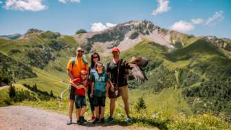 Famiglia in posa con un'aquila in estate sullo sfondo dell'imponente montagna di Malbun, nel Liechtenstein.