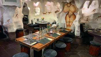 Primo piano di un accogliente ristorante con tavoli e sedie in legno, decorato con fiori e candele.
