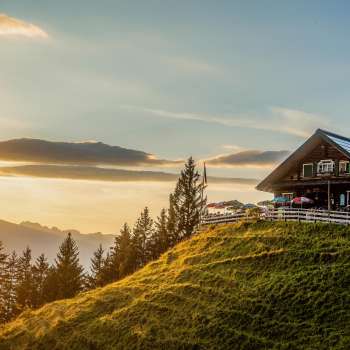 Rifugio Gadafura su un prato di montagna soleggiato con vista sulle montagne e sul tramonto
