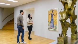 Una coppia osserva i dipinti nella luminosa galleria del museo d’arte del Liechtenstein, con sculture moderne in primo piano.