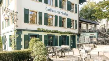 Terrazza invitante con tavoli e sedie in legno di fronte alla Gasthaus zum Hirschen