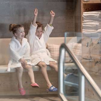 Due bambini in accappatoio si godono l'area benessere dell'Hotel Gorfion - vacanze in famiglia all'insegna del benessere a Malbun.
