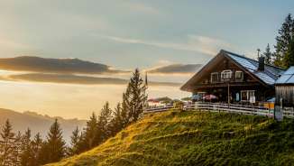 Rifugio Gafadurahütte su una verde collina del Liechtenstein al tramonto con vista panoramica sulle montagne