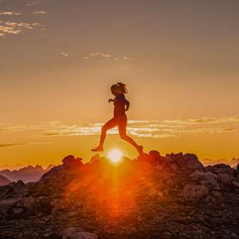 Due trail runner attraversano un crinale roccioso all'alba in Liechtenstein, nella luce dorata dell'alba