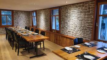 Elegante sala da pranzo con lunghi tavoli in legno, pareti in pietra e decorazioni moderne