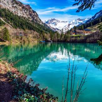 Il lago cristallino di montagna lago Gänglesee a Steg, Liechtenstein, circondato da boschi, montagne e verde primaverile