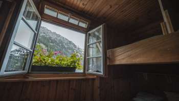 Vista dalla finestra del dormitorio: vista del paesaggio montano da un semplice dormitorio con letti a castello nel rifugio Gafadurahütte