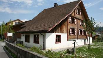 Storico Küefer-Martis-Huus con facciata tradizionale in legno e persiane rosse a Ruggell, Liechtenstein.