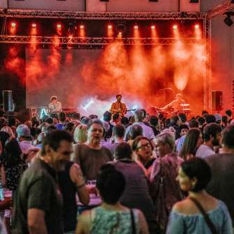 Concerto del gruppo Baba Shrimps al Festival FL1.LIFE con luci rosse sul palco e un pubblico numeroso