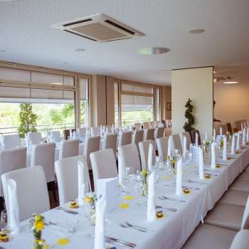 Sala decorata a festa con elegante disposizione dei tavoli, coperte bianche e dettagli raffinati