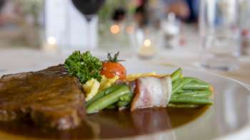 Primo piano di un piatto principale con verdure verdi, pancetta e salsa cremosa sul piatto