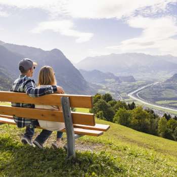 Due escursionisti siedono su una panchina e si godono la vista sulla valle del Reno