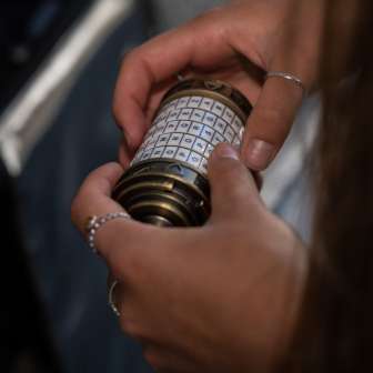 Primo piano delle mani con un misterioso lucchetto a combinazione nella Malbun Escape Room