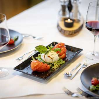 Insalata di pomodori freschi e mozzarella con vino rosso su una tavola imbandita al JUFA Hotel Malbun