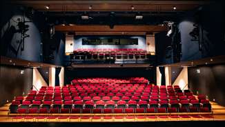 Vista dal palcoscenico delle file di sedili rossi e dell'illuminotecnica nel moderno auditorium del Teatro TAK Liechtenstein