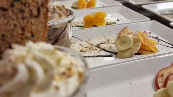 Tavola riccamente apparecchiata con bicchierini da dessert, frutta e guarnizioni per un buffet dolce