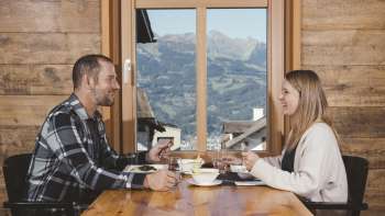 Una coppia si gode una piacevole cena con vista sulle montagne in un ambiente rustico in legno