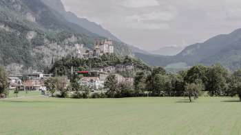 Maestosa vista della rocca di Gutenberg a Balzers, circondata da campi verdi e dalle imponenti Alpi.