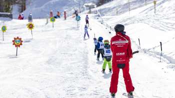 Maestro di sci e bambini sulla seggiovia nell Area giochi Malbi Park