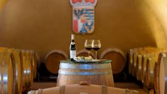 Vista della cantina con botti di legno e tavolo coperto con vino e formaggio presso le Cantine di Corte del Principe del Liechtenstein