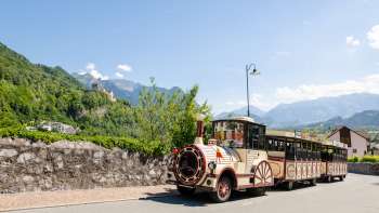 Il trenino turistico Vaduz attraversa un paesaggio pittoresco con una vista sulle Alpi sullo sfondo. Il trenino turistico Vaduz attraversa un paesaggio pittoresco con una vista sulle Alpi sullo sfondo.