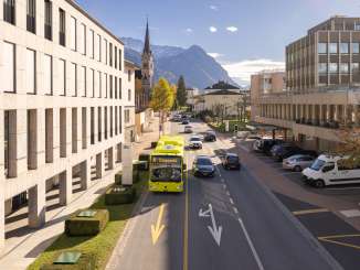 Un autobus LIEmobil attraversa Vaduz sullo sfondo delle Alpi e dell'architettura moderna