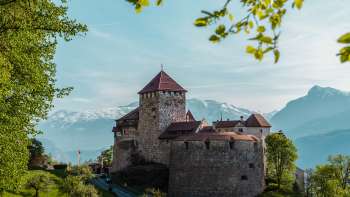 Vista pittoresca del castello di Vaduz, immerso nel verde di colline e foreste.