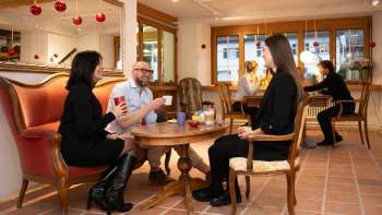 Tre persone nel Keramikcafé in Liechtenstein con caffè e tè in un'accogliente atmosfera lounge.
