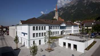 L'edificio Domus di Schaan con la sua facciata bianca e la vista sulla chiesa parrocchiale: un centro culturale e di incontro nel cuore del Liechtenstein