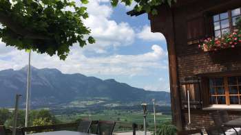 Edificio tradizionale con terrazza soleggiata e panorama montano sullo sfondo