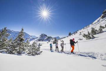Gruppo in escursioni con le ciaspole attraverso il paesaggio innevato del monte Schönberg , vicino a Malbun, sotto un radioso sole invernale.