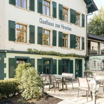 Terrazza invitante con tavoli e sedie in legno di fronte alla Gasthaus zum Hirschen