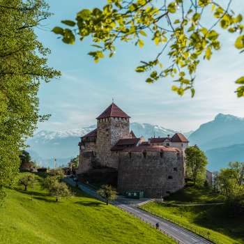 Vista pittoresca del castello di Vaduz, immerso nel verde di colline e foreste.
