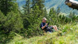 Una persona in sedia a rotelle si gode il paesaggio alpino a Malbun - accesso senza barriere alla natura nel Liechtenstein
