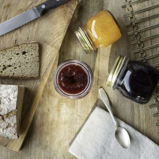 Marmellata fresca Holder con pane di fattoria e vasetti di marmellata su una tavola di legno: godetevi una colazione tradizionale in Liechtenstein