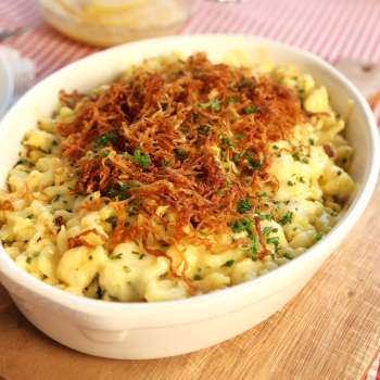 Käsknöpfle (gnocchetti al formaggio) con cipolle fritte - serviti in un piatto su una tavola di legno