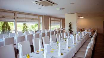 Sala decorata a festa con elegante disposizione dei tavoli, coperte bianche e dettagli raffinati