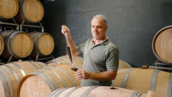 Harry Zech preleva il vino dalla barrique per degustarlo con una pipetta: la tradizione enologica di Schaan.