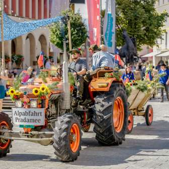 Trattore decorato a festa con rimorchio alla discesa alpina di Pradamee 2020 in Liechtenstein, circondato da spettatori