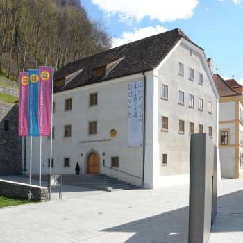 Vista del museo nazionale del Liechtenstein a Vaduz con edifici storici e bandiere colorate