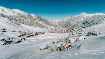 Veduta aerea di Malbun in inverno con le case di legno innevate, immerse nel paesaggio alpino del Liechtenstein