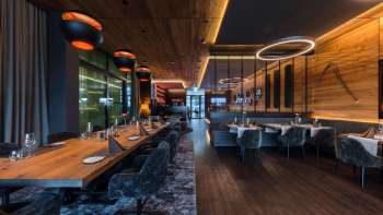 Elegante sala da pranzo con elementi di illuminazione moderni e rivestimenti in legno alle pareti.