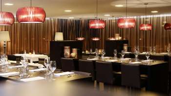 Sala da pranzo elegante con mobili scuri, lampade rosse di design e un ambiente elegante