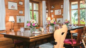 Invitante sala da pranzo con soffitto in legno, tavolo decorato con cura e vista sulla finestra luminosa