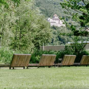 Tranquillo prato per prendere il sole con lettini in legno nel Parco Naturale di Haberfeld, con vista sul castello sullo sfondo.