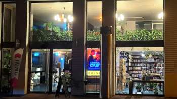 Vista esterna illuminata del cinema Skino di Schaan di notte, con grandi vetrate e un'atmosfera invitante.