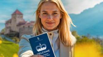 «Pass attrazioni BENVENUTO» " - Scoprire Vaduz e dintorni / generato da AI Donna con in mano il «Pass attrazioni BENVENUTO» davanti al castello di Vaduz in un campo fiorito