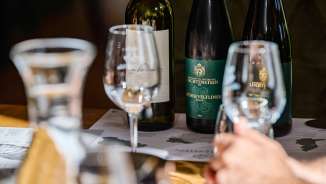 Primo piano di bicchieri e bottiglie di vino della Hofkellerei Liechtenstein durante una degustazione professionale di vini con Grüner Veltliner